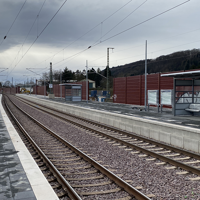 Bahnsteige an einer zweigleisigen elektrifizierten Bahnstrecke mit Wartehäuschen.