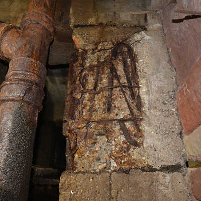 An den Trägern des Anbaus ist der Beton abgeplatzt, die Stahlbewehrung weist Rostschäden auf und liegt frei.