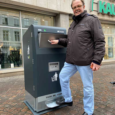 Der für die Innenstadt zuständige Dezernent Ralf Britten testet eine der neuen Mülltonnen in der Simeonstraße. Wichtig: Aufs Pedal unten treten, damit sich die Klappe öffnet.