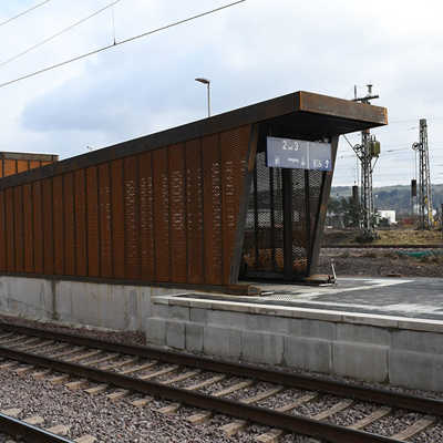Ein Aufgang mit einem Wetterschutz aus Edelrost mündet auf einen Bahnsteig