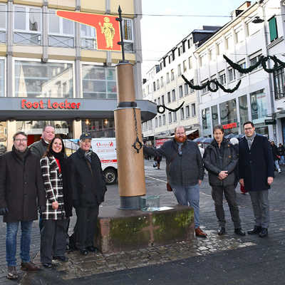 Jan Tschickardt, Chef der Zimmerei Tschickardt, Kulturamtsleiterin Elvira Classen, der Vorsitzende der Trier Gesellschaft Karlheinz Scheurer (vorne, von links nach rechts) sowie weitere Mitglieder des Vereinsvorstands und Kulturdezernent Markus Nöhl (3. von rechts) freuen sich darüber, dass der Pranger wieder an seinem angestammten Platz die Innenstadt schmückt.