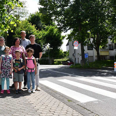 Baudezernent Dr. Thilo Becker (hinten) und Hortleiterin Marion Heintz (2. Reihe Mitte) freuen sich mit Kindern und Mitarbeitenden über den neuen Fußgängerüberweg Im Hopfengarten. 