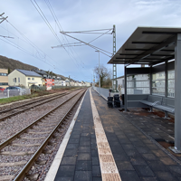 Bahnsteig mit Wartehäuschen an einer zweigleisigen elektrifizierten Bahnstrecke